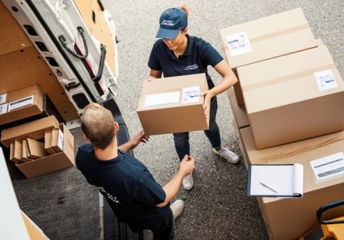 Delivery workers handling packages beside a delivery van