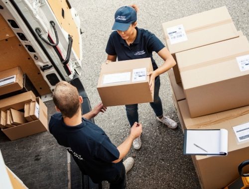 Delivery workers handling packages beside a delivery van