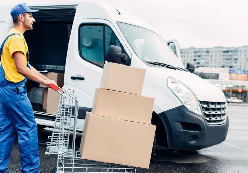 Delivery worker loading packages beside a delivery van